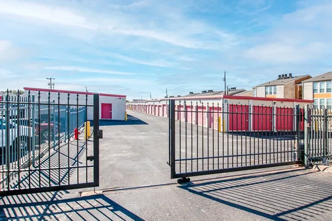 Secure gated entrance to storage facility with metal fencing and drive-up unit access